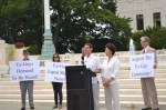 Three people with signs, two speakers, and a podium