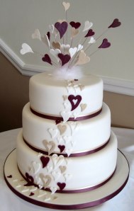 A white wedding cake with heart decorations.