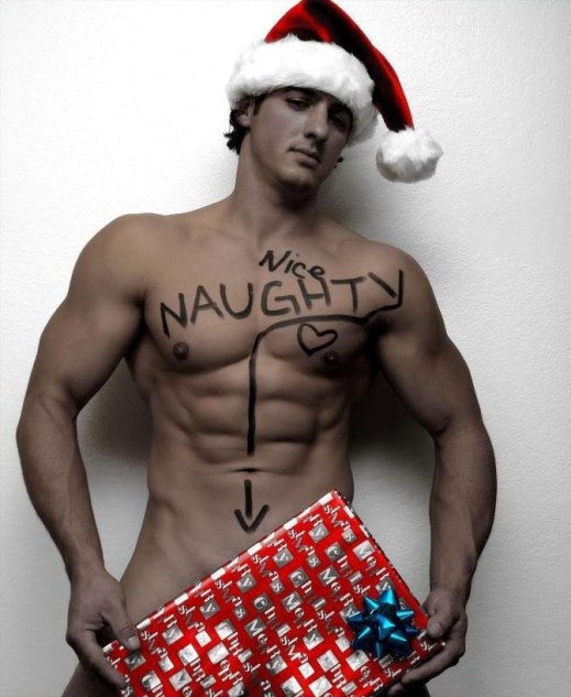 Nearly naked guy in Santa hat holds present. The words Nice and Naughty are written across his chest.