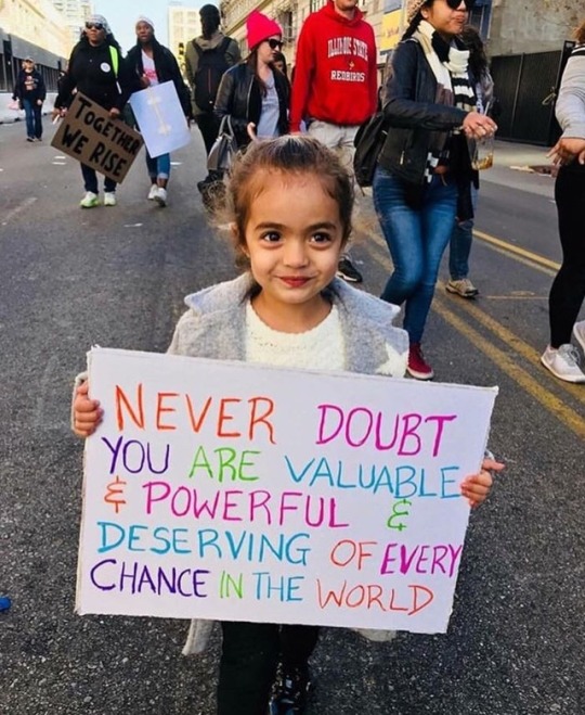 “Never doubt you are valuable & powerful & deserving of every chance in the world.” Little girl's sign quotes Hillary.