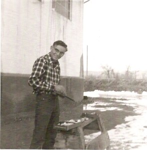 My dad stands outside on a snowy day, with a gun and his gun cleaning kit.